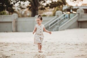 Family Photographer - a little girl walks along the sand at Balmoral beach