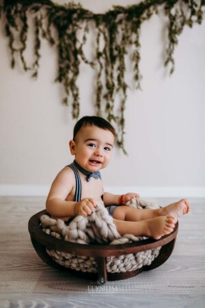 Baby boy sitting on a wool blanket in a wooden bowl prop