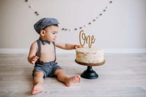 Little boy touching his first birthday cake before smashing it