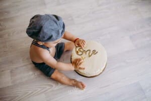 A little boy sits in front of his cake, touching the icing