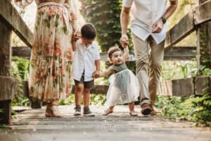 Family Photographer - Children stand between their parents on a boardwalk