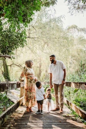 Family Photographer - parents hold their children between them on a boardwalk