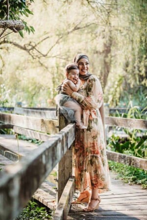 Family Photographer - A mother cuddles her baby girl as they stand on a boardwalk