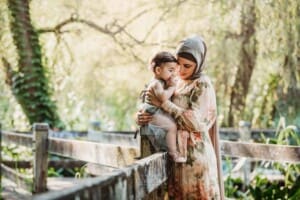 Family Photographer - A mother cuddles her baby girl standing on a boardwalk