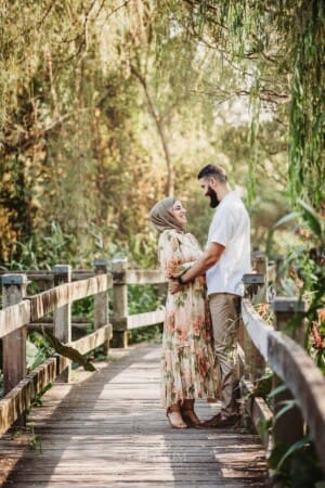 Family Photographer - A couple cuddle as they stand on a boardwalk