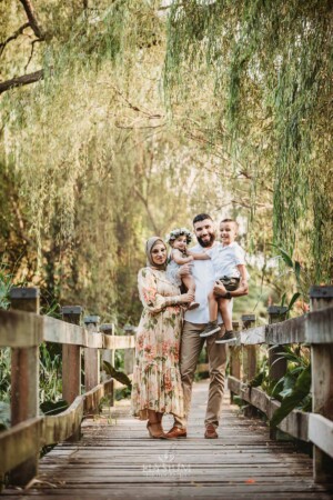 Family Photographer - A family stand cuddled together on a boardwalk
