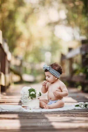 Family Photographer - A baby sits on a boardwalk in front of her birthday cake