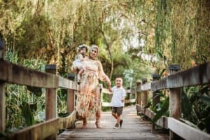 Family Photographer - A mother holds her children as they stand on a boardwalk