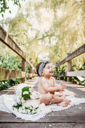 Family Photographer - A little girl does a cake smash sitting on a boardwalk