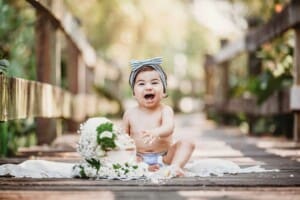 Family Photographer - A little girl sits on a boardwalk about to smash a cake