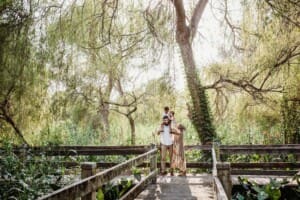 Family Photographer - parents hold their children on their shoulders standing on a boardwalk