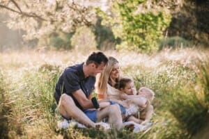Family Photographer - A family sit cuddling in a grassy field