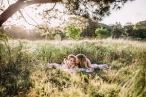 Family Photographer - A mum kisses her little girl as they lay on a rug