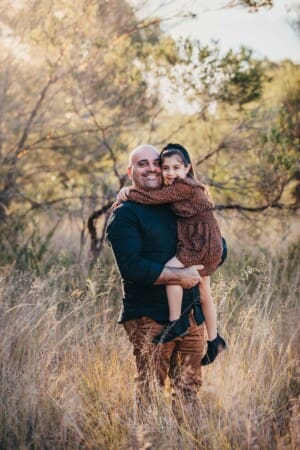 Family Photographer - A father holds his daughter standing in long grass