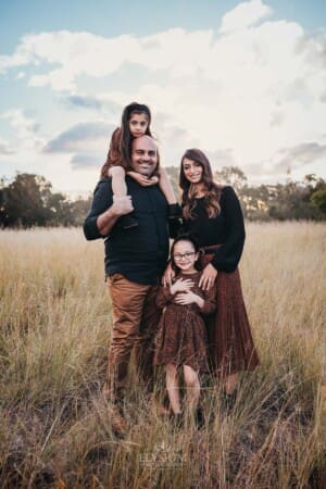 Family Photographer - A family stands in long grassy field at sunset