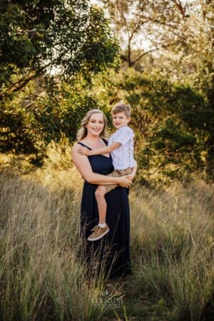 A mother hugs her little boy as they stand in Sydney bushland at sunset