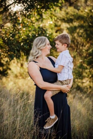 A mother hugs her little boy as they stand in Sydney bushland at sunset