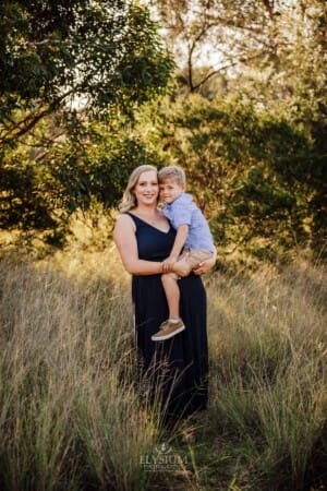 A mother hugs her little boy as they stand in Sydney bushland at sunset