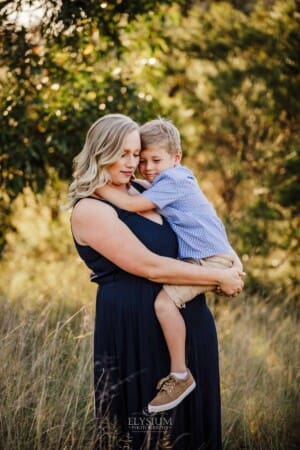 A mother hugs her little boy as they stand in Sydney bushland at sunset