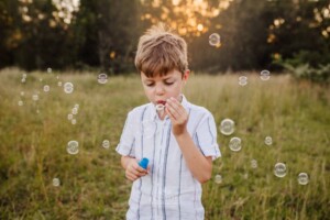 A little boy blowing bubbles at sunset