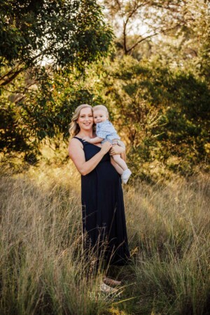A mother hugs her baby boy as they stand in Sydney bushland at sunset