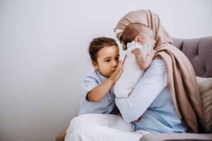 Newborn session - A little boy pats his baby sister on the back, mum cuddles them