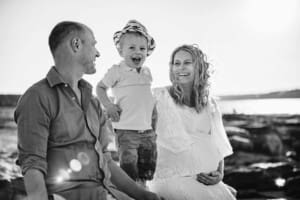 Maternity session - a little boy sits between his parents, his mum holds her pregnant belly