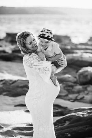 Maternity session - a pregnant mother hugs her little boy as the giggle