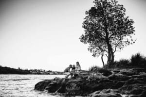 Maternity session - a family cuddle around the pregnant mum, sitting on beach rocks