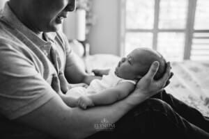 Newborn session - a fathers hands gently cradle his newborn son