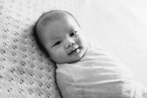 Newborn session - a baby lays wrapped on a white blanket