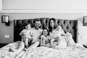 Family session - parents hug their kids on the bed