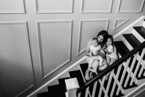 Family session - a mother cuddles her daughters as they sit on the stairs