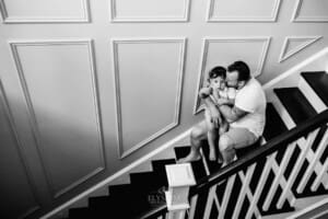 Family session - a father hugs his son as they sit on the stairs