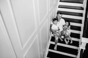 Family session - a dad sits on the stairs with his children