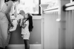 Family session - a mum holds her baby, her sister kisses the baby