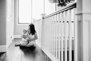 Family session - a mother holds her baby girl in her lap, sitting on the floor