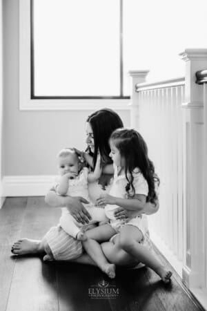 Family session - a mother hugs her children, sitting on the floor