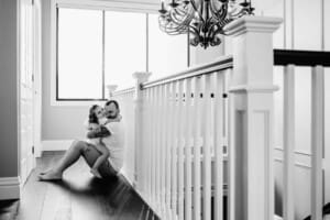 Family session - a little girl sits in her dads lap, kisses him on the cheek