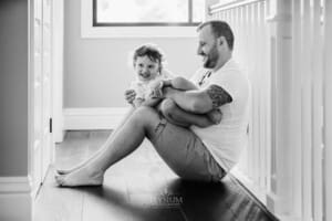 Family session - a father tickles his son sitting in his lap
