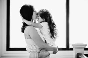 Family session - a mother holds her daughter and kisses her forehead