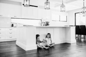 Family session - 2 children eat ice blocks, sitting under the kitchen bench
