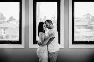 Family session - parents hug standing in front of a window