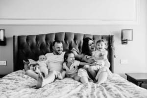 in home session, family sits on the bed and laughs