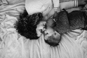 Newborn session - a mother and son lay on a bed, giving nose kisses