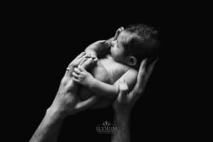 Newborn session - a fathers hands gently hold his baby