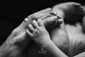 Newborn session - a baby wraps his tiny hand around his dad's finger