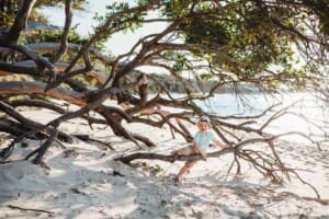Beach session - a little boy sits in branches of a tree on the sand