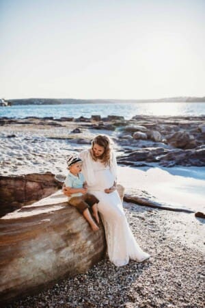 Maternity session - a pregnant mum sits with her little boy on a beach