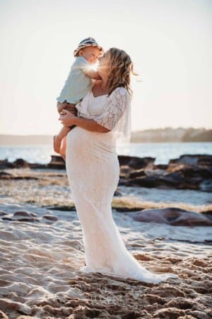 Maternity session - a pregnant mum hugs her son, on a beach at sunset